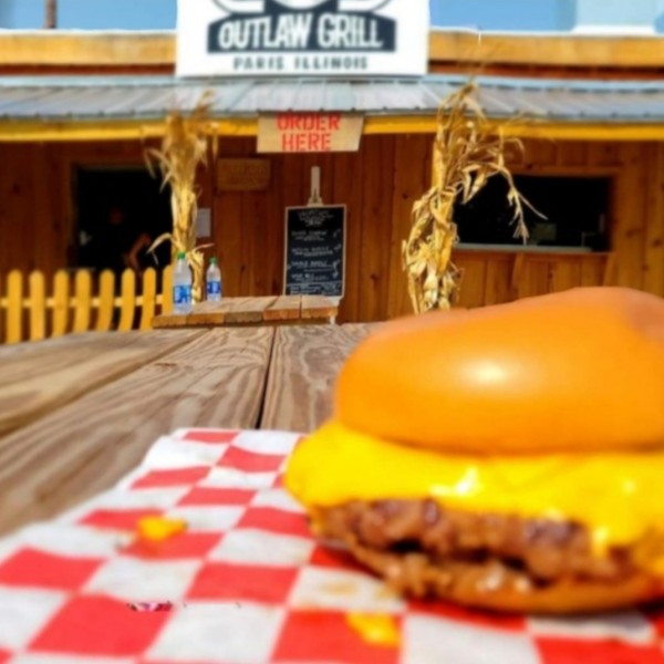 A burger in on a picnic table in front of a restaurant